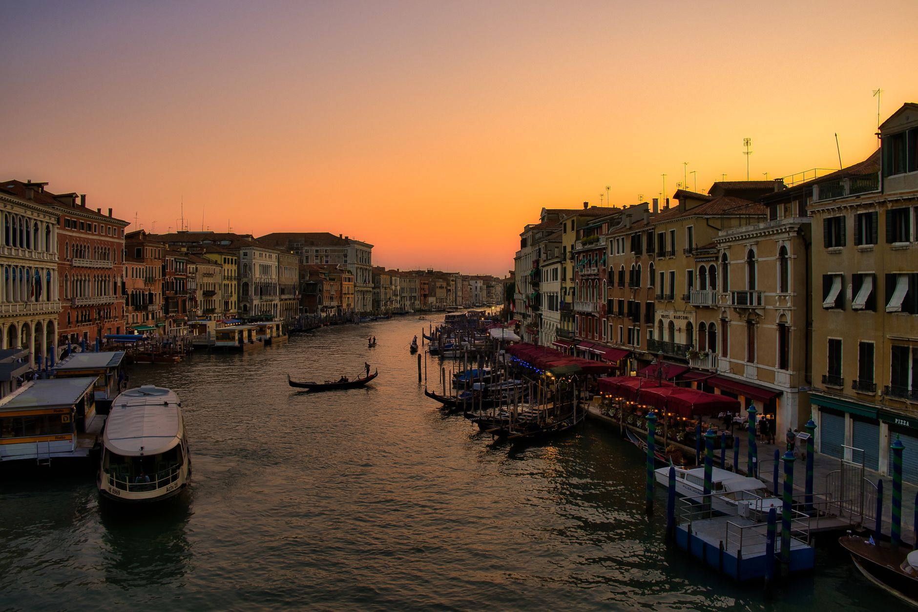 Sunset over Venice's Grand Canal, with gondolas gliding by historic buildings