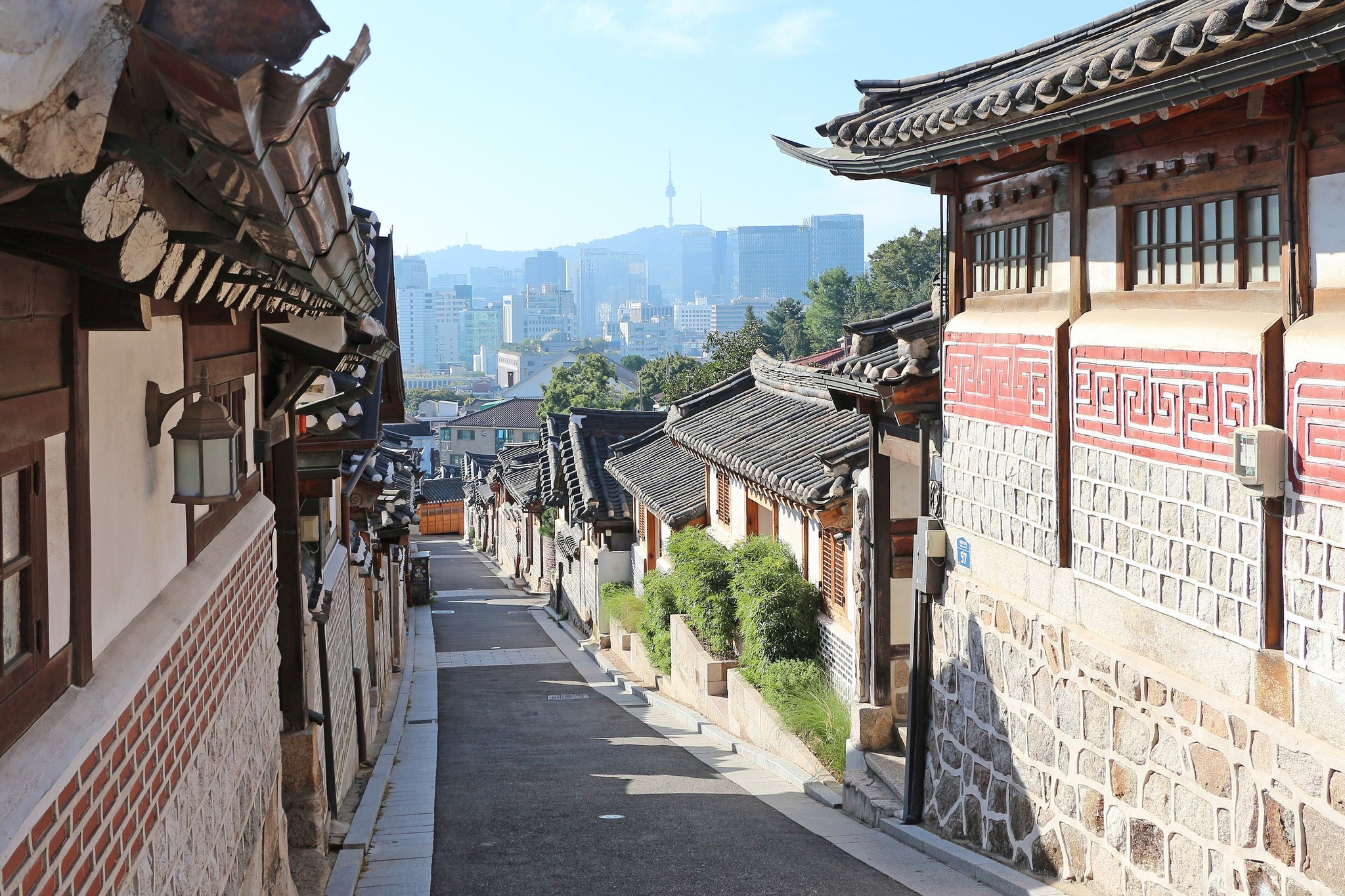 A steep Bukchon lane of tiled hanok roofs with N Seoul Tower closing the view