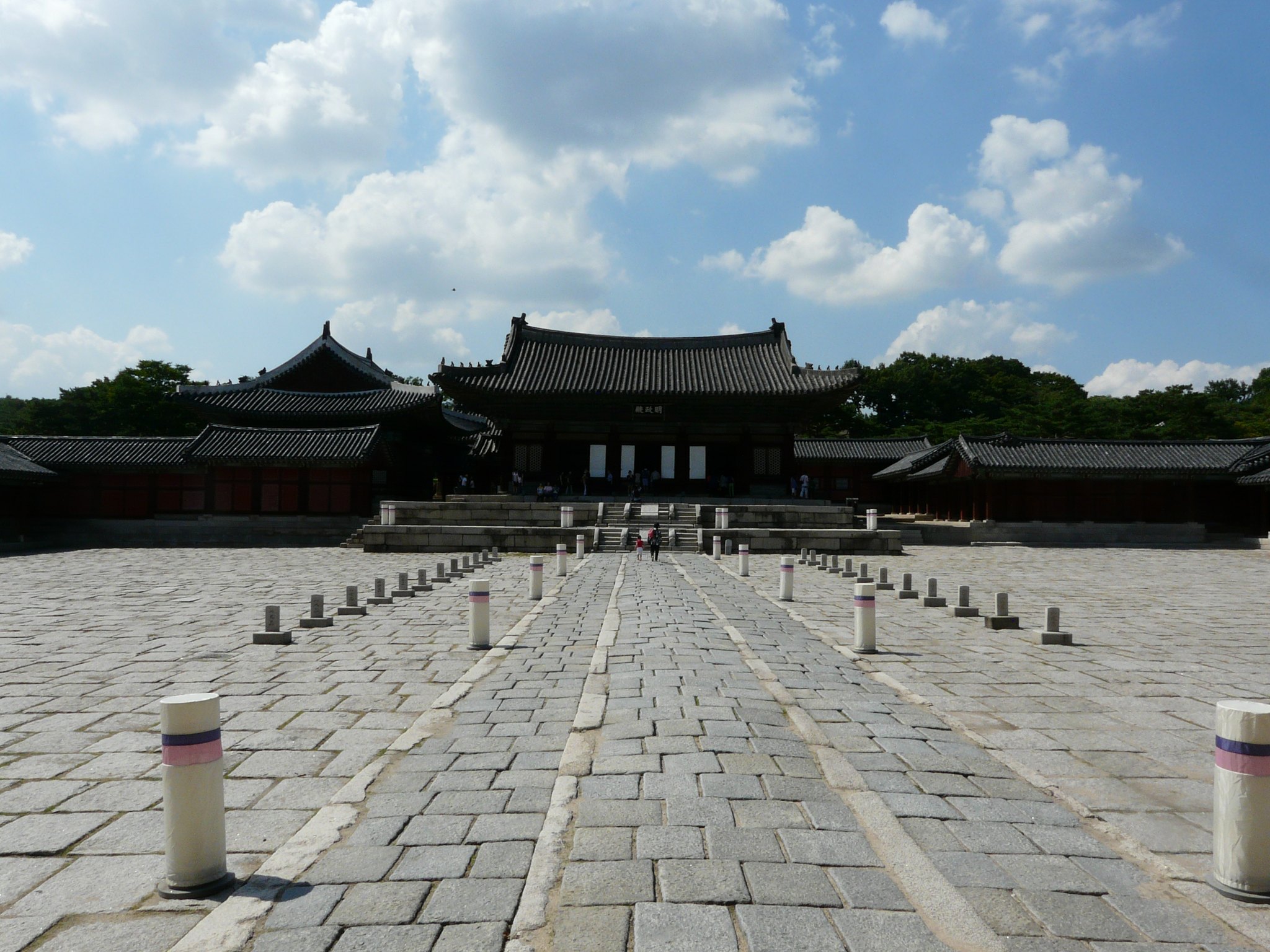 The empty flagstone courtyard of Changgyeonggung under a sky of broken cloud