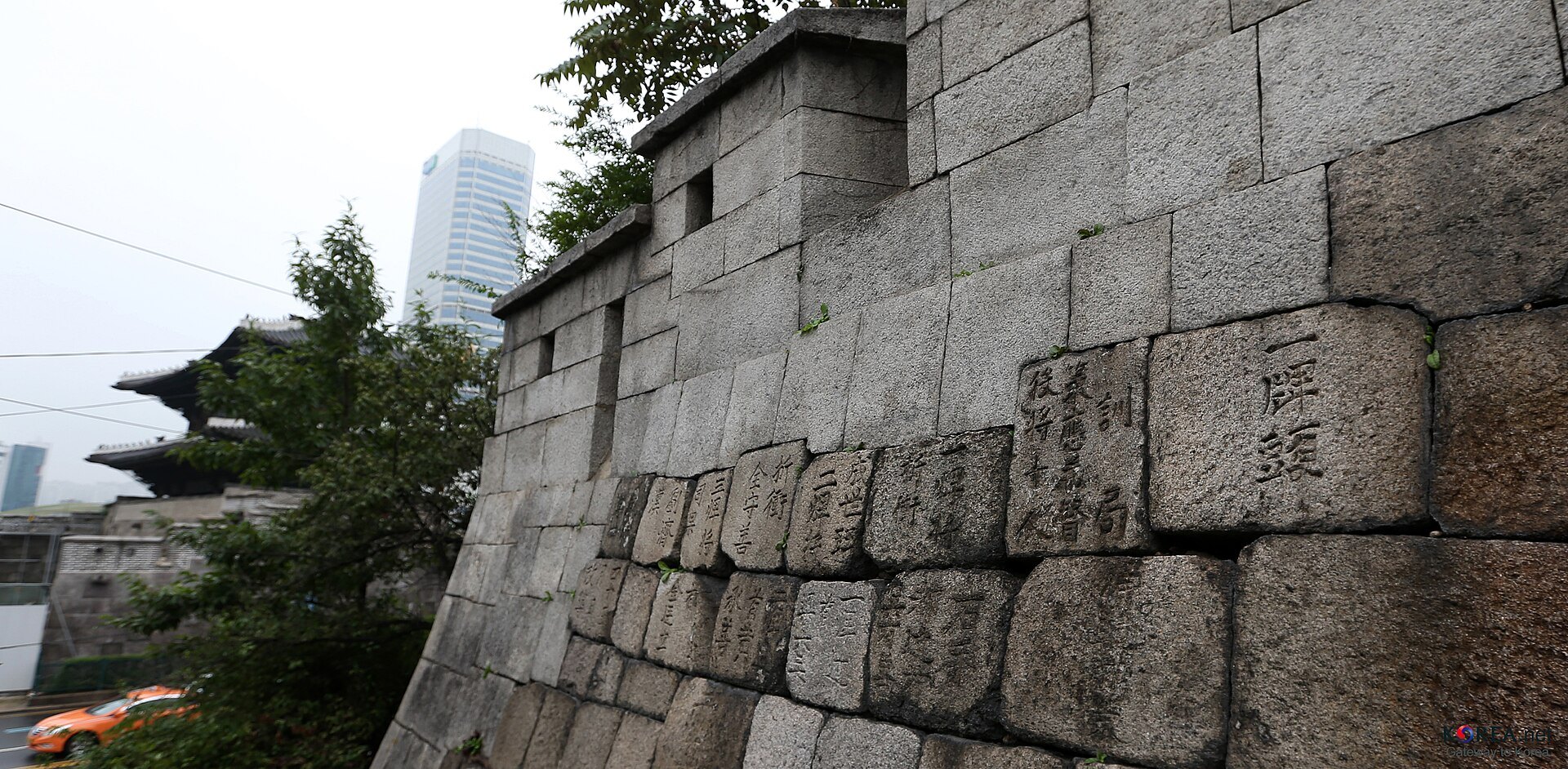 The cut stone blocks of the Seoul City Wall with a gate beyond it