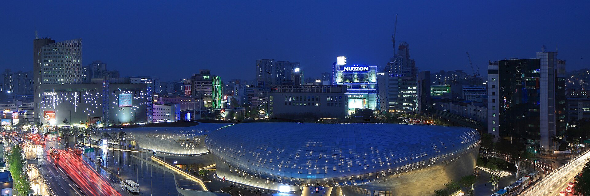 The Dongdaemun Design Plaza lit at night, its curved shell above the road