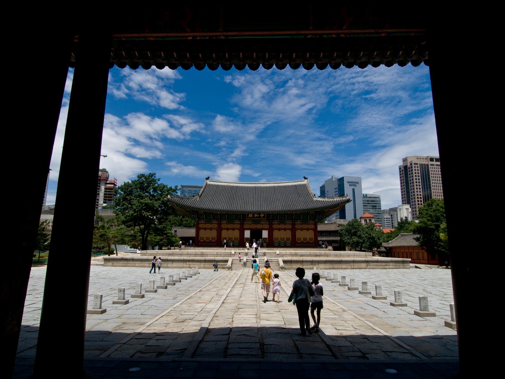 The Junghwajeon hall framed in a palace gateway, with visitors in hanbok on the steps