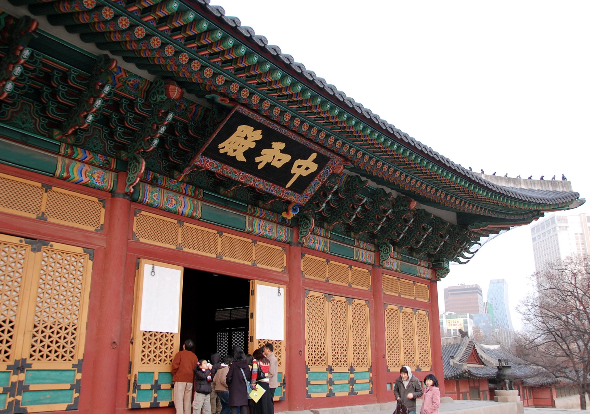 The red-and-gold entrance of Junghwajeon with visitors passing under the name board
