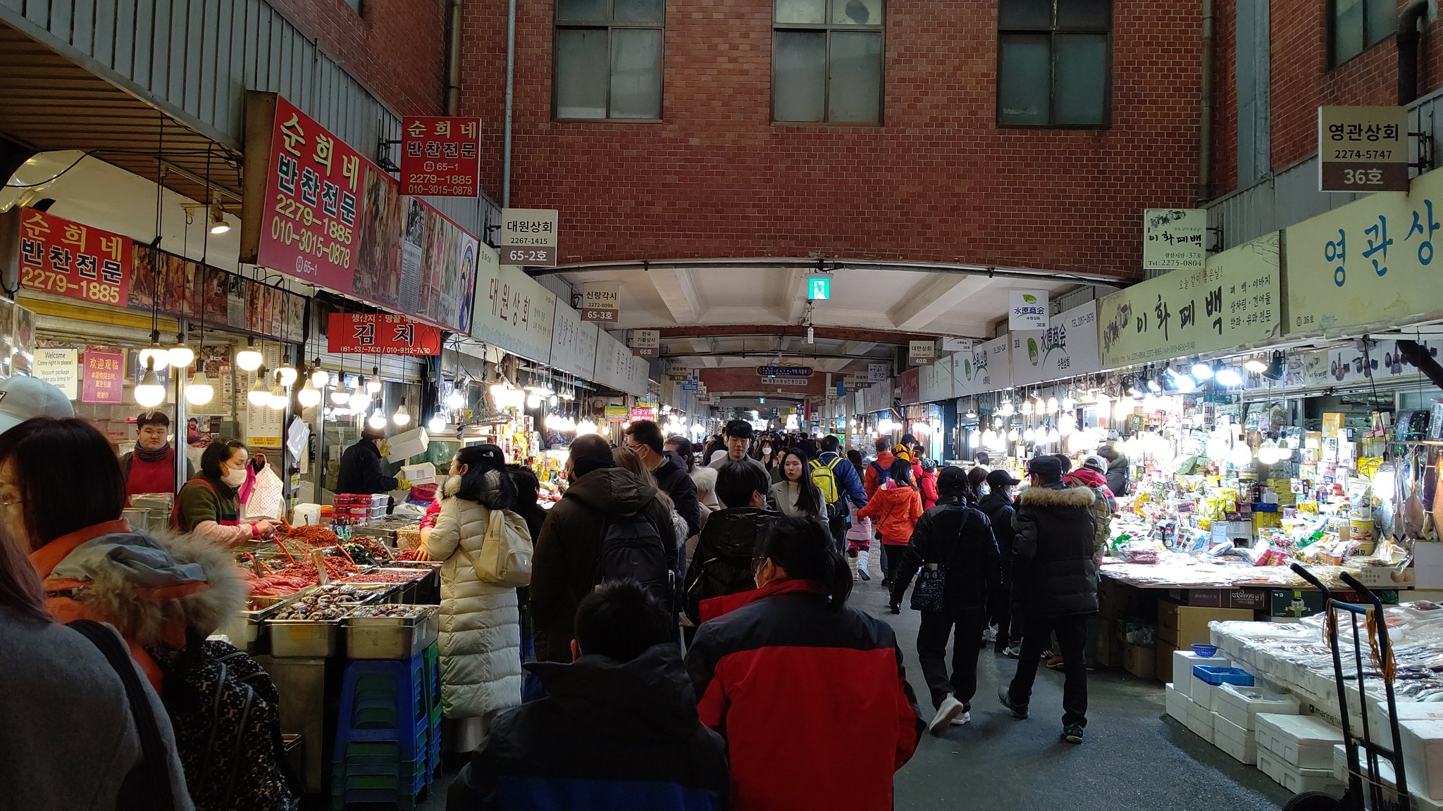 The packed central aisle of Gwangjang Market between rows of food stalls
