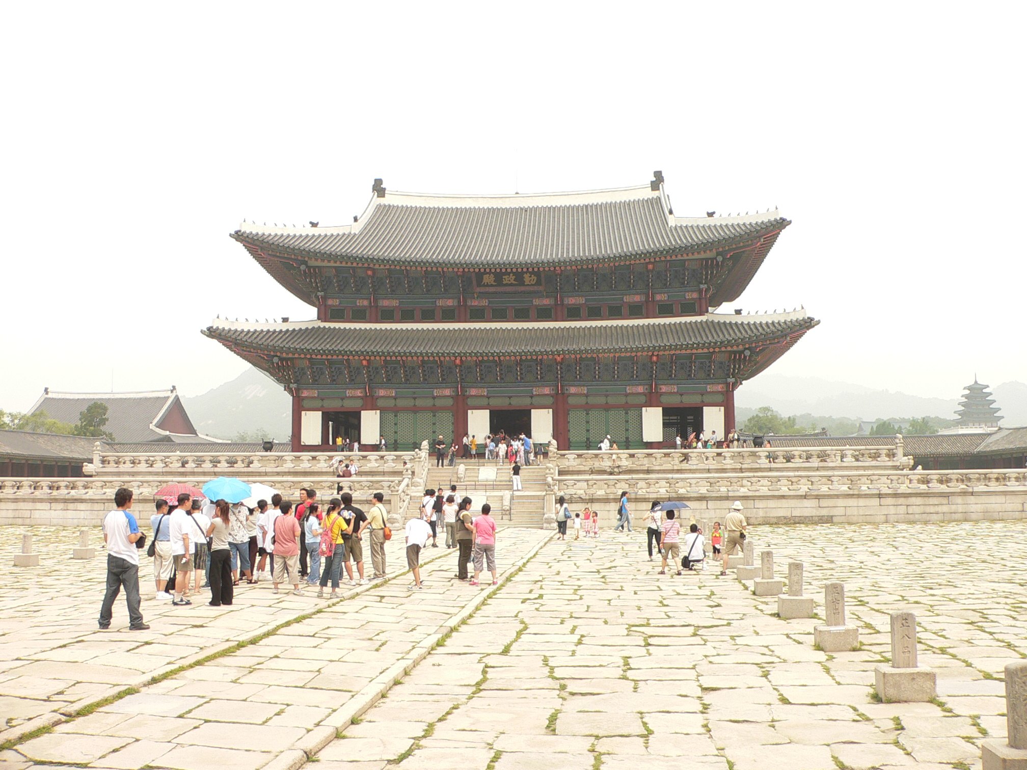 Visitors crossing the flagstone courtyard of Gyeongbokgung towards the throne hall