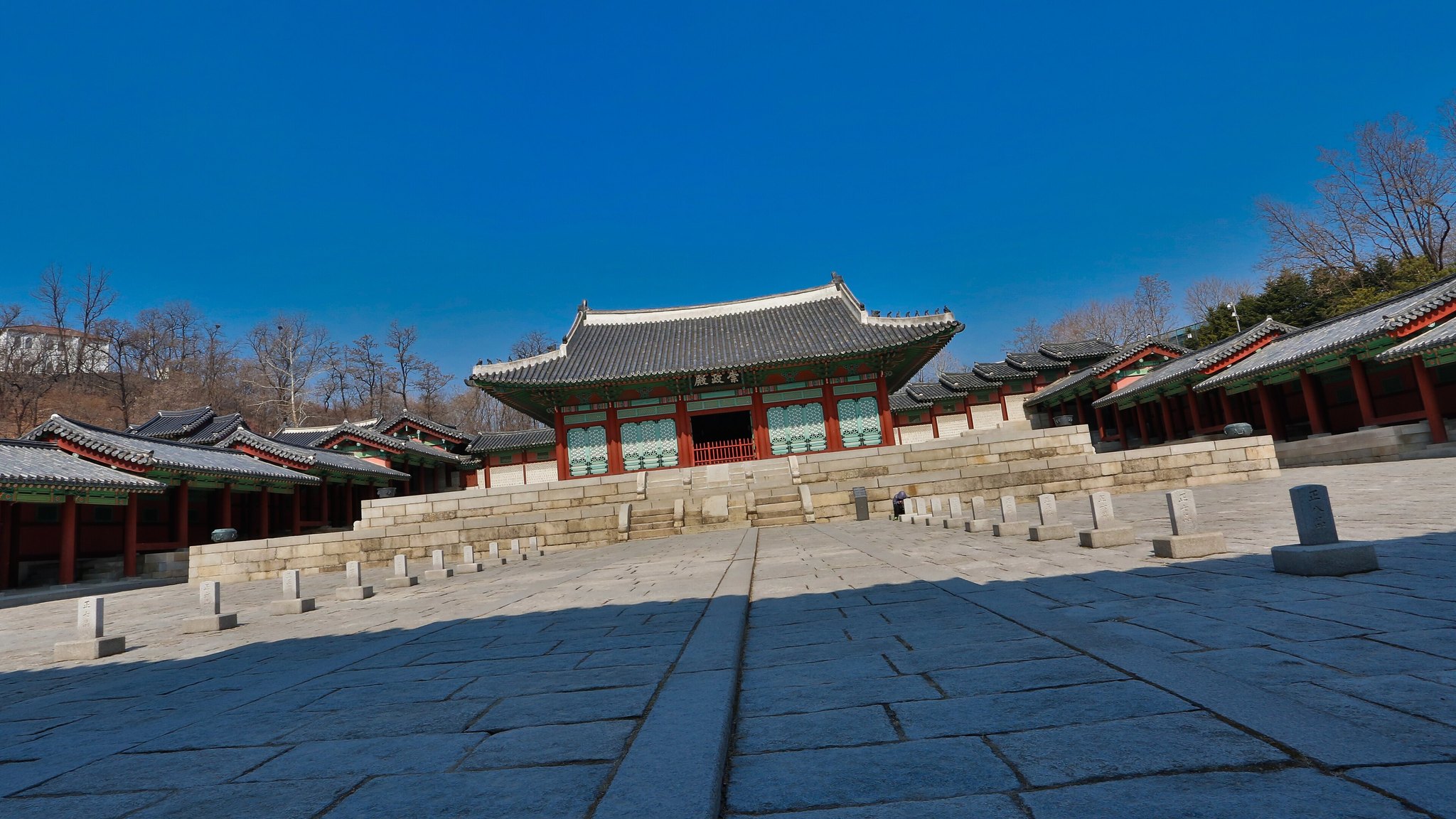The empty courtyard of Gyeonghuigung under a deep blue sky, with nobody in it