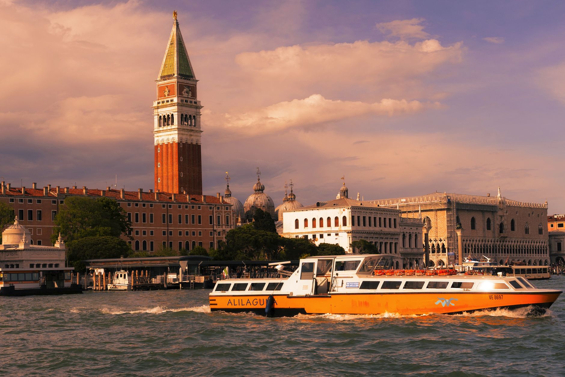 Venice canal featuring vaporetto and Campanile di San Marco at sunset