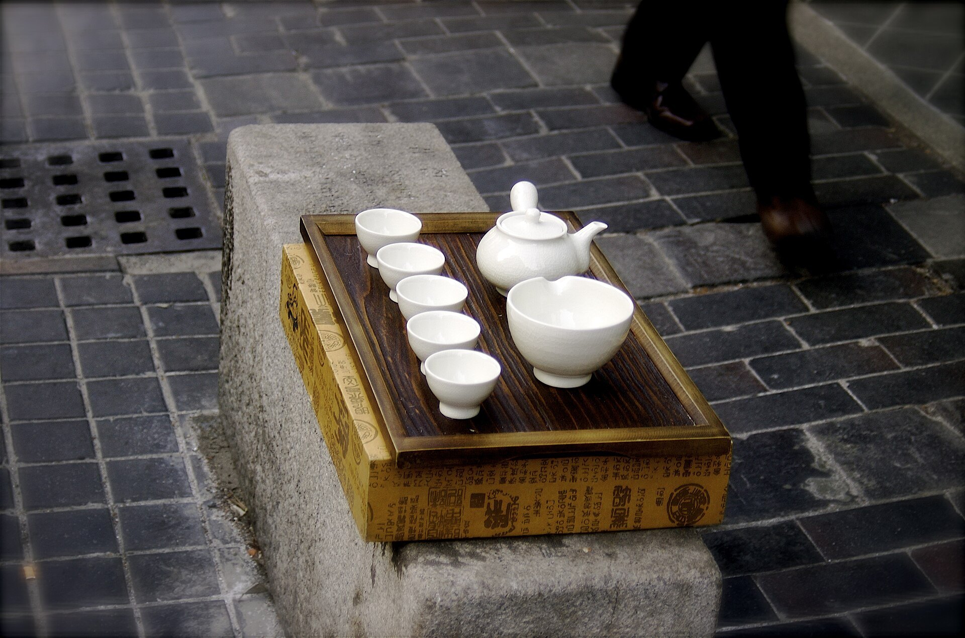 A wooden tea tray with white cups set out on the pavement in Insadong