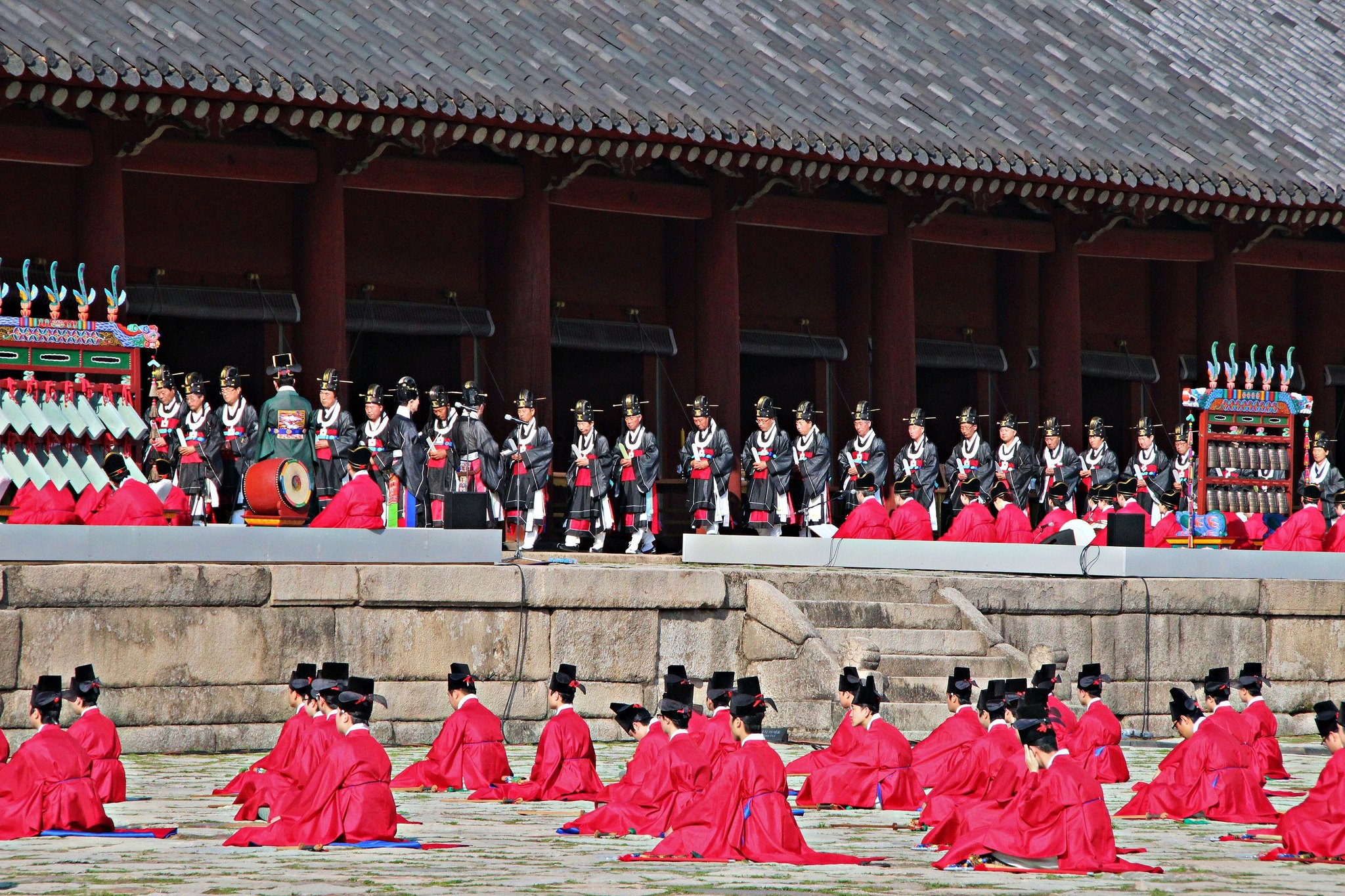 Ritual musicians in red robes performing the Jongmyo Jeryeak on the shrine terrace