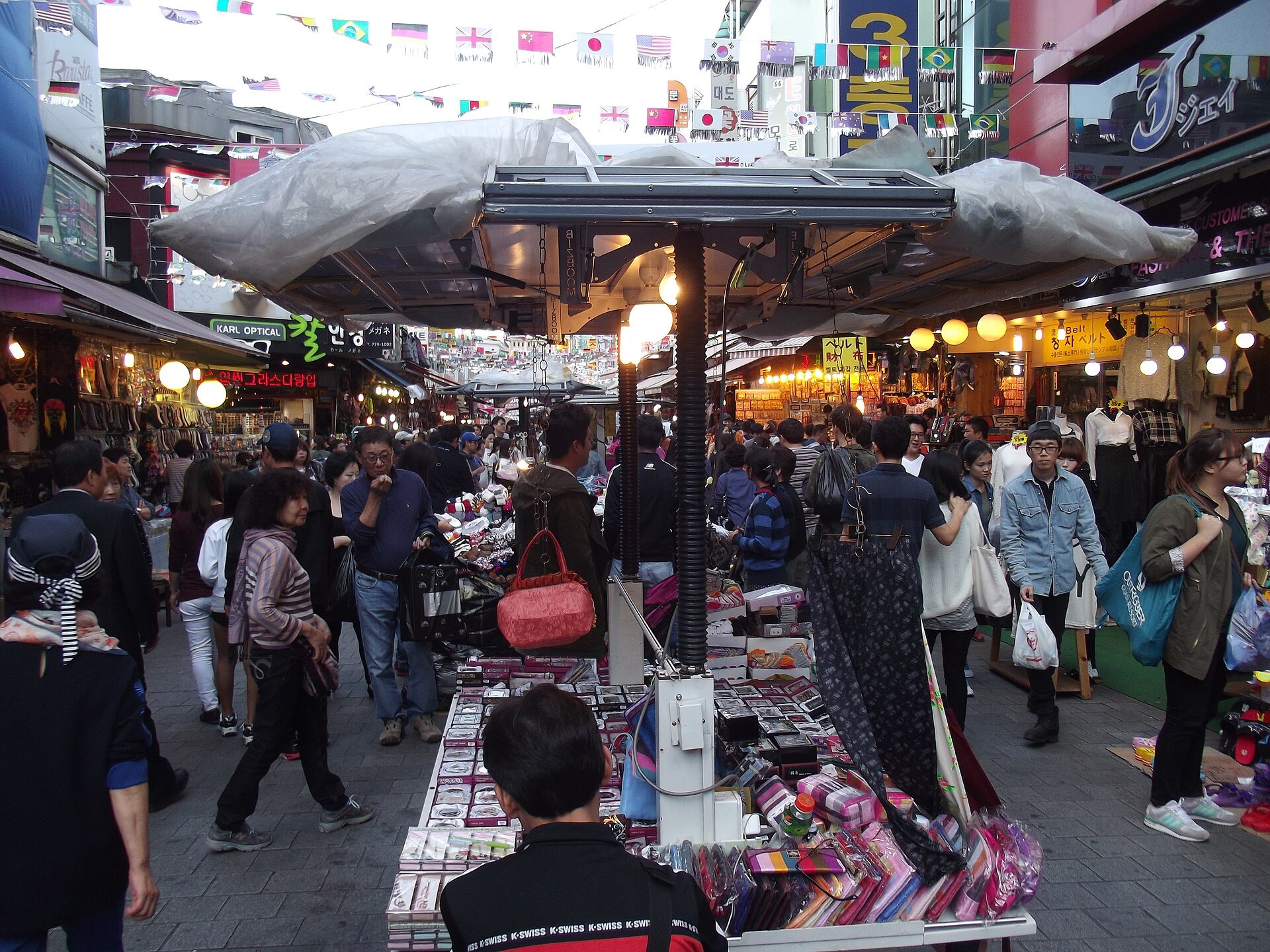 Shoppers under the awnings of a Namdaemun Market lane