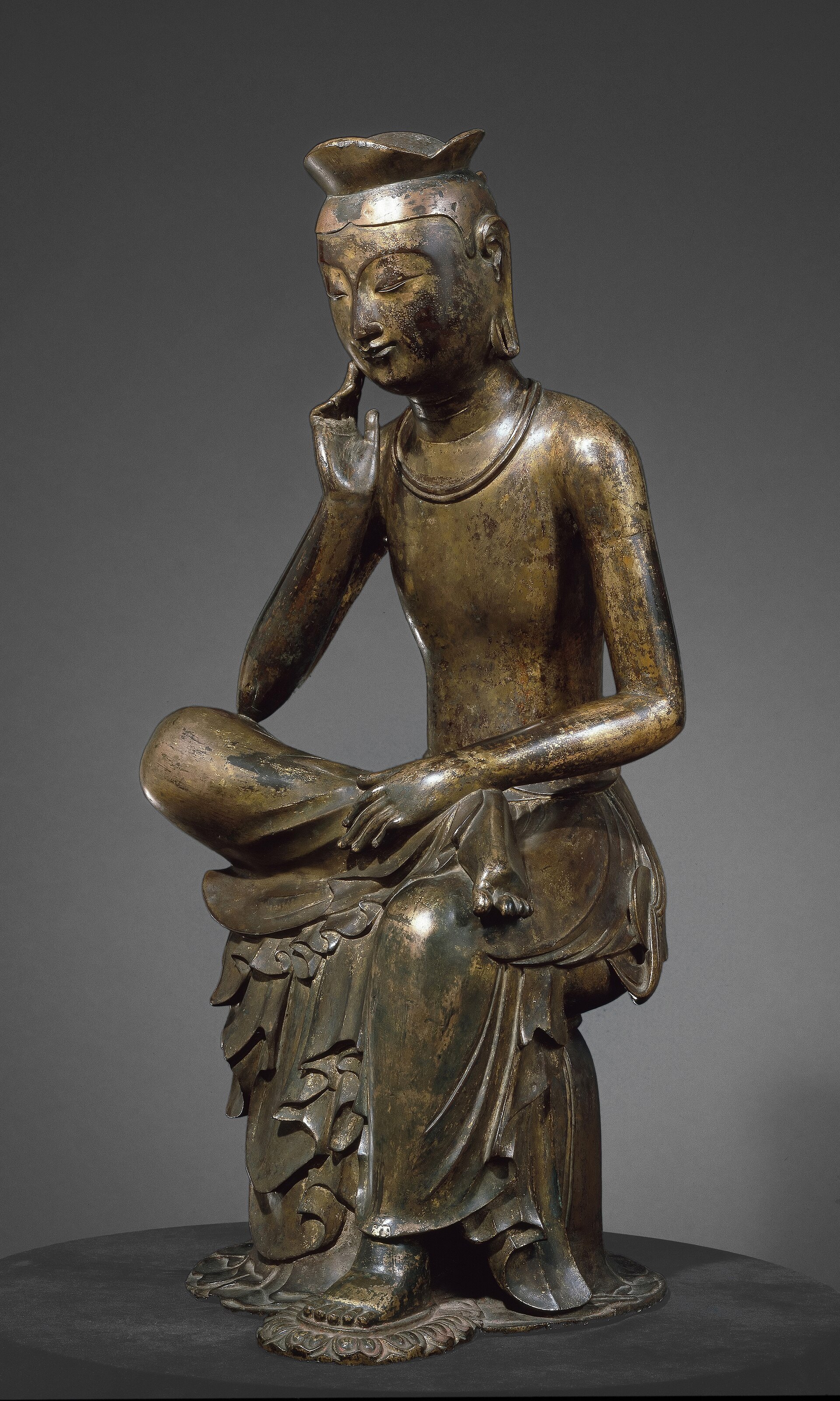 The gilt-bronze Pensive Bodhisattva seated with one hand raised to its cheek