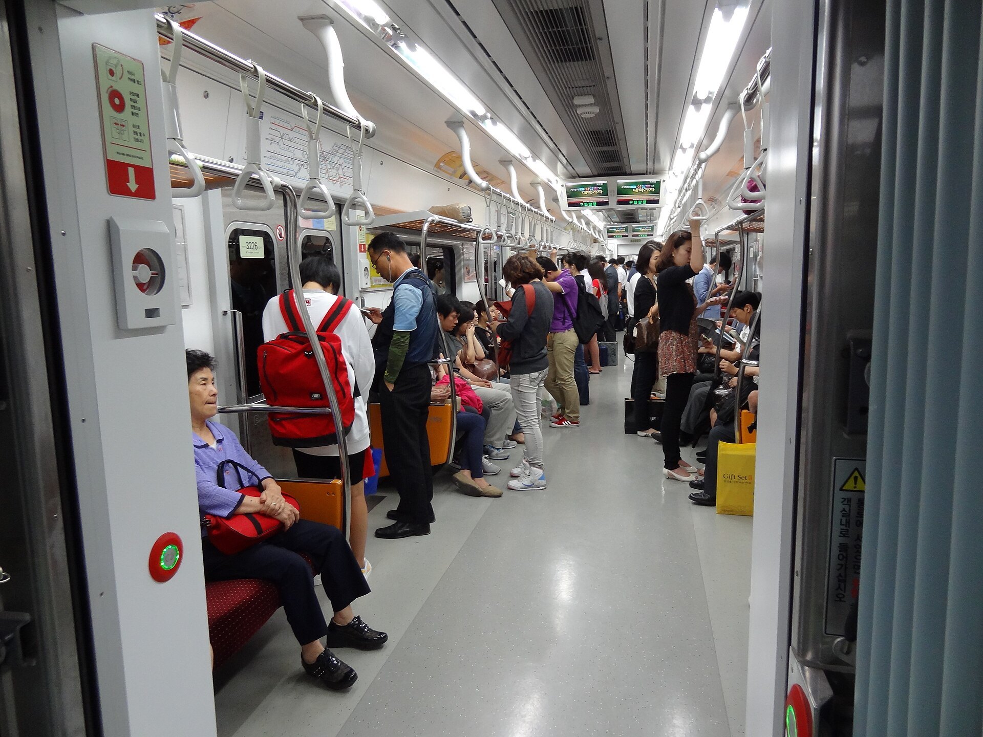 A busy Seoul metro car with passengers standing and seated